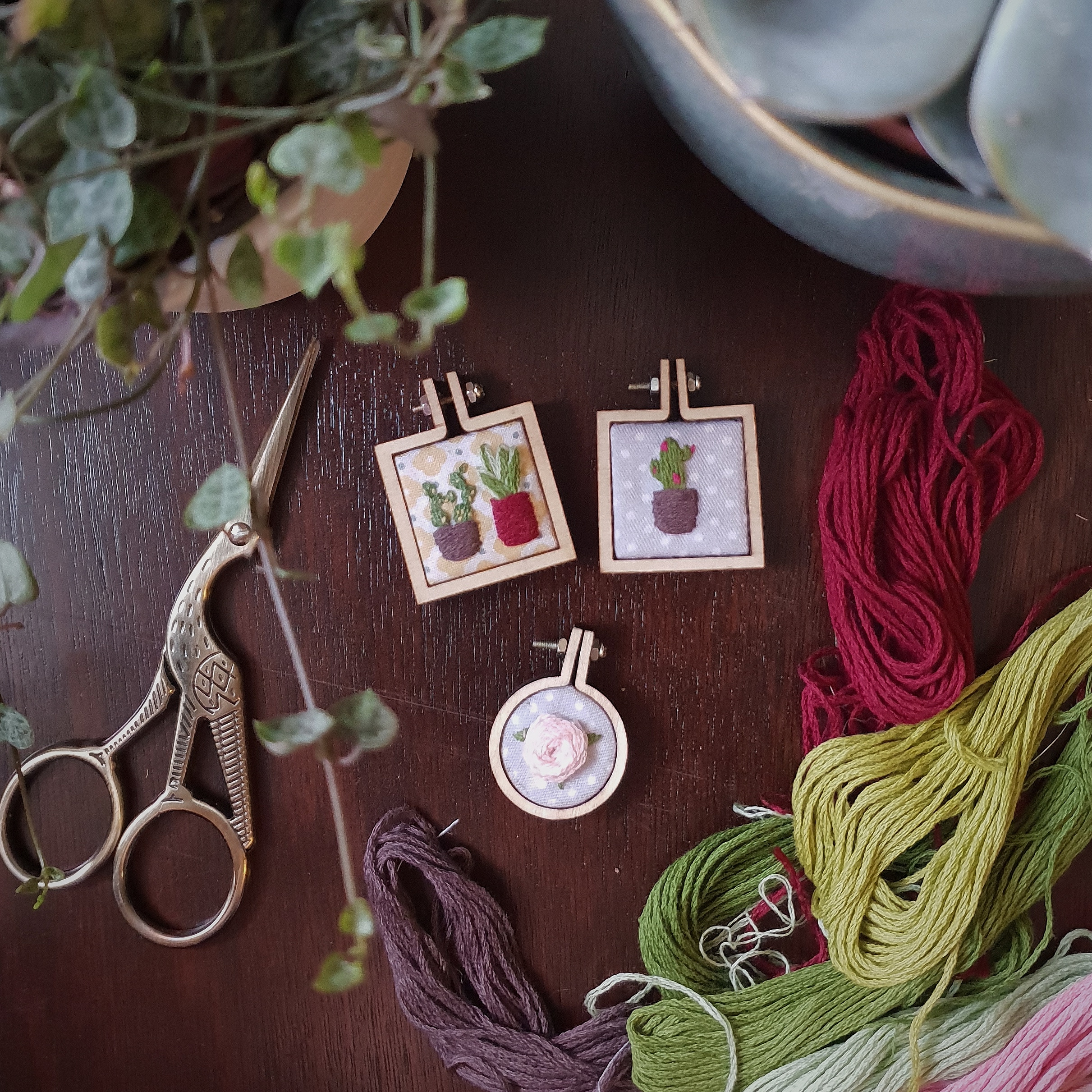 Flatlay photography featuring embroidered necklaces, thread and plants