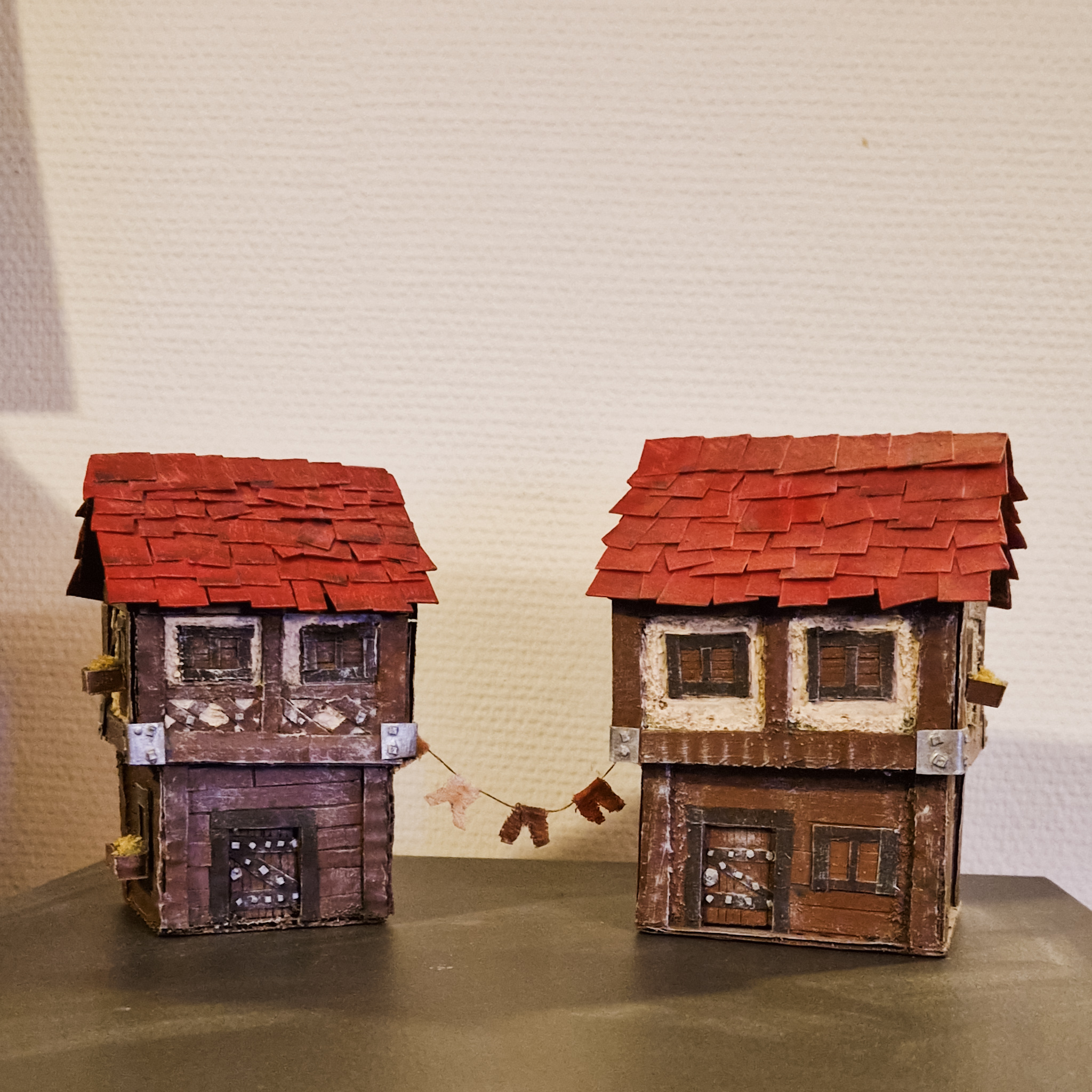 Two miniature houses in wattle and daub architecture style with clothes line between them